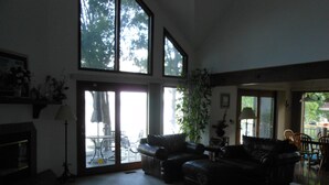 Amplia sala de estar con chimenea, ventanas grandes y comedor con mobiliario para exterior.
