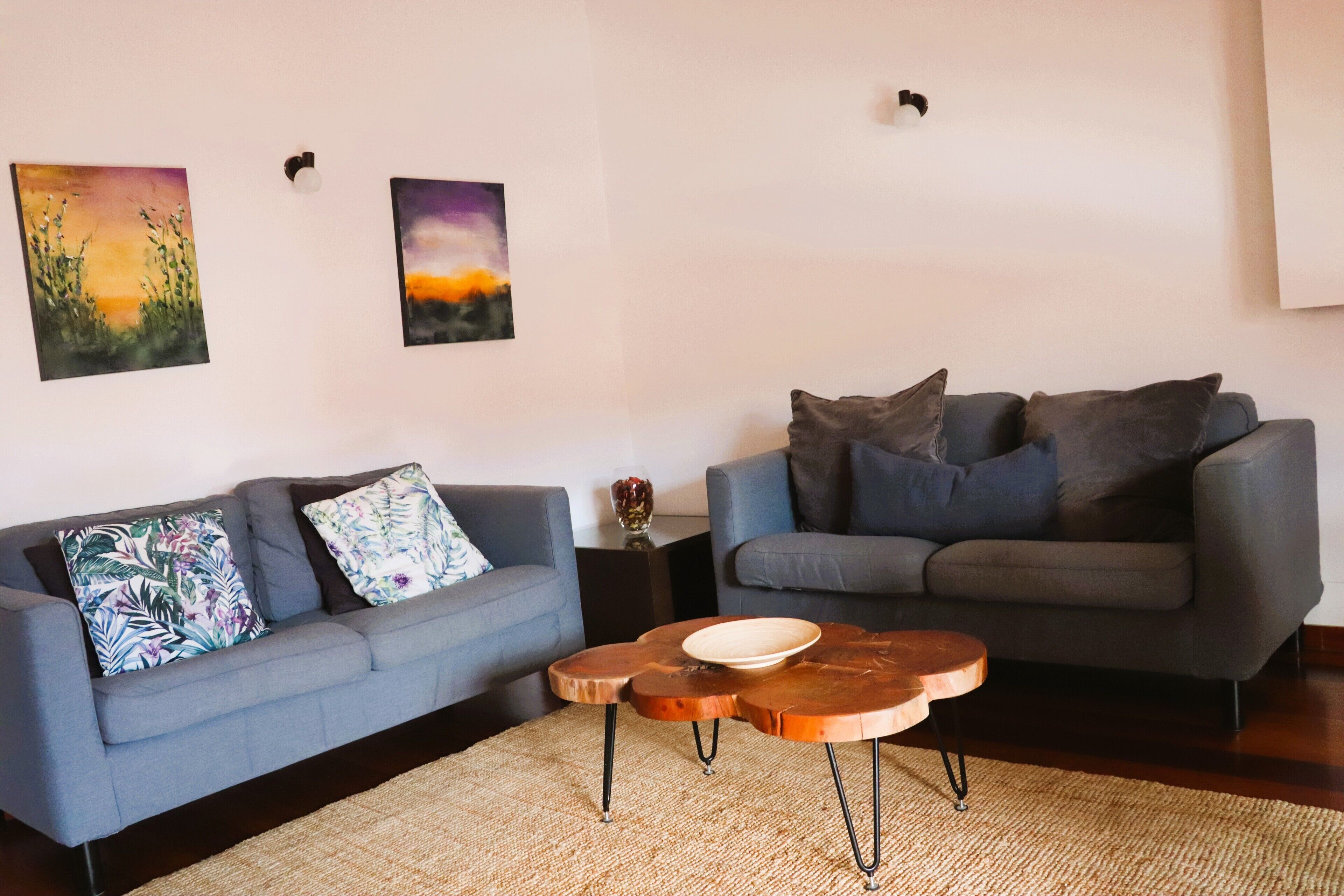 A living room with two grey sofas, a woven rug, and a wooden coffee table.