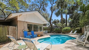 A backyard with a swimming pool, lounge chairs, and a wooden deck. - Pup Friendly Home w/ Fully Fenced Yard! (Hilton Head Island)