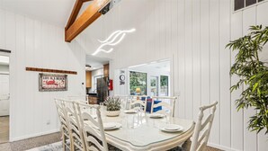 A dining area with a glass-top table, white chairs, and a patterned rug. - Pup Friendly Home w/ Fully Fenced Yard! (Hilton Head Island)