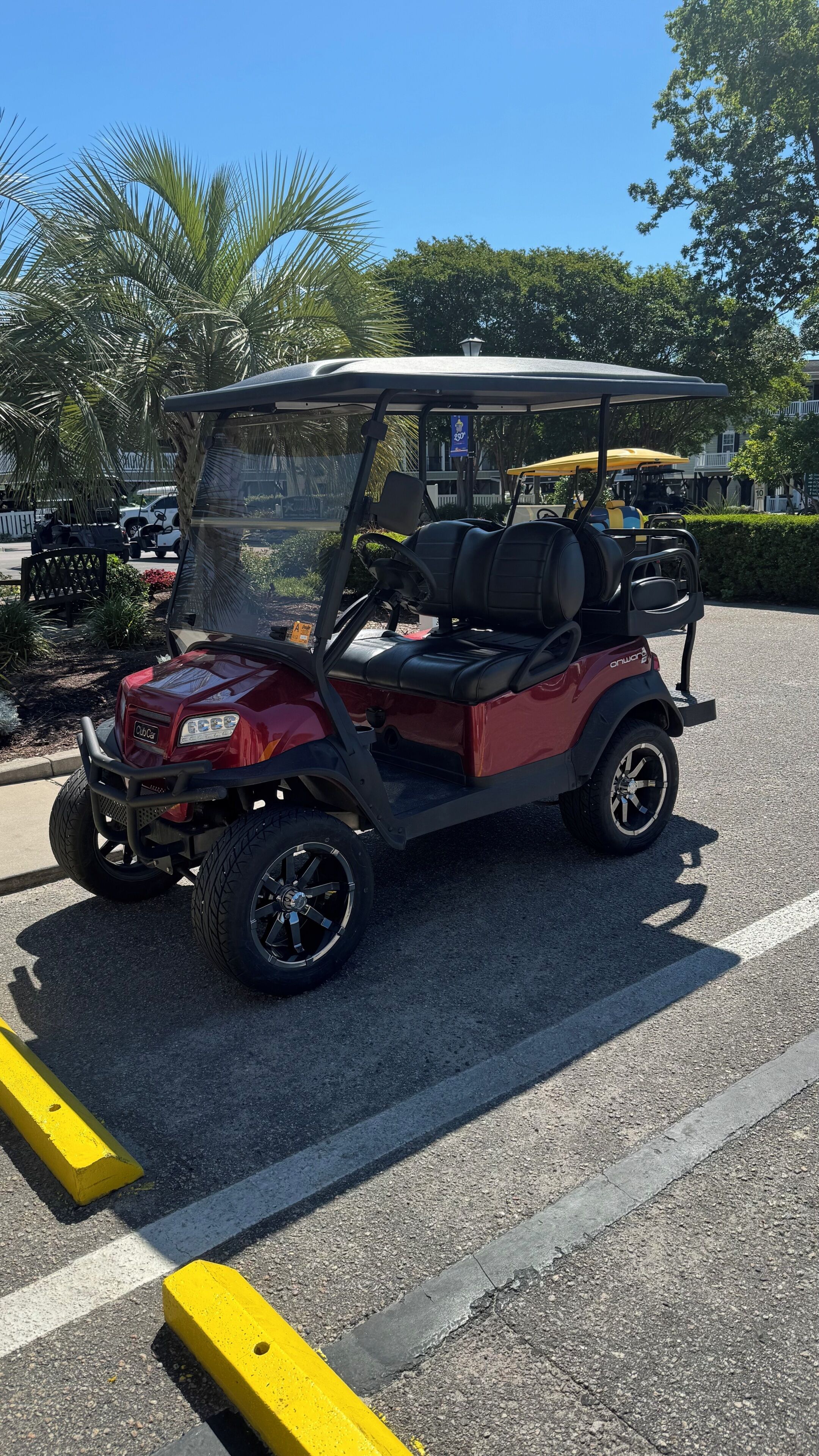 A red golf cart parked in a parking lot with a clear blue sky in the background.