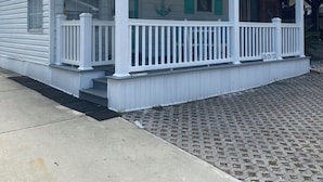 Ein weißes, eingeschossiges Haus mit überdachter Veranda, einer Haustür und einem Briefkasten.