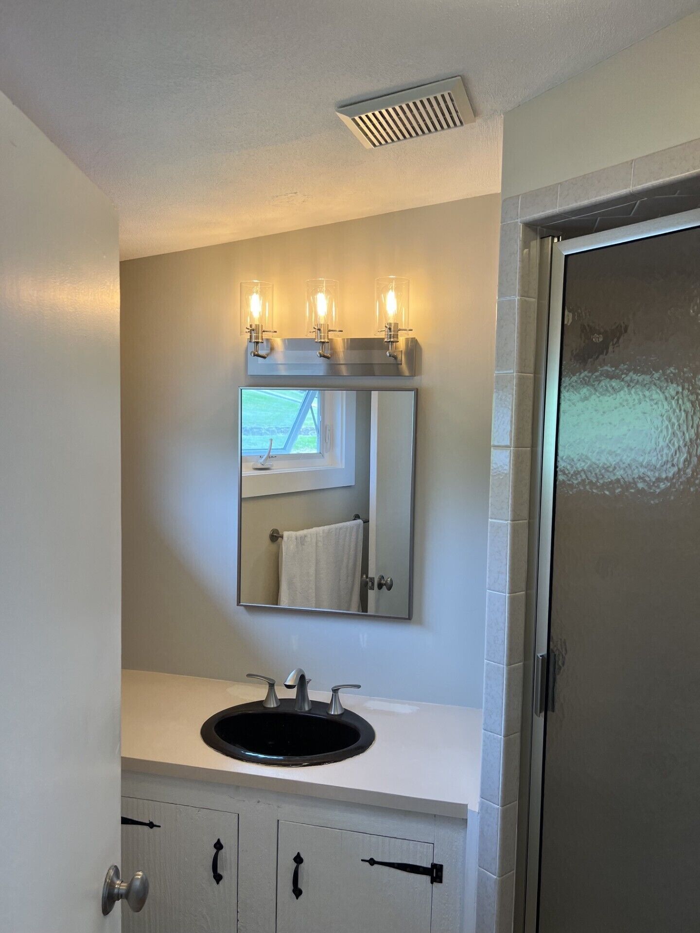 A bathroom with a sink, mirror, and a window above the mirror.