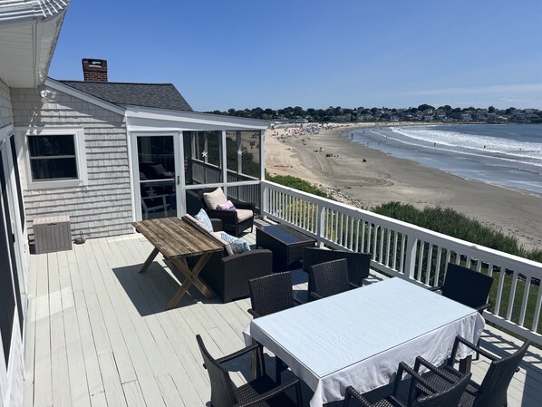 A deck with outdoor furniture overlooking a beach. - Spectacular Private Beach Home, why walk when you can live right on the beach. (Narragansett)