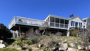 Ein zweigeschossiges Haus mit Balkon, überdachter Veranda und Garage.