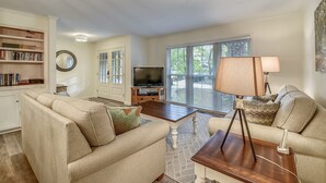 A living room with a sofa, coffee table, TV, and a lamp. - Pet Friendly 3BR w/ Screened Porch & Amenities (Hilton Head Island)