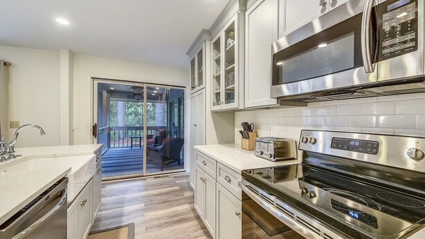 A modern kitchen with stainless steel appliances, white cabinetry, and a view to a deck. - Pet Friendly 3BR w/ Screened Porch & Amenities (Hilton Head Island)