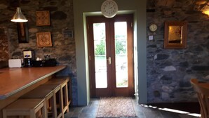 Une cuisine chaleureuse avec un mur en pierre, un bar en bois et une horloge au-dessus de la porte.