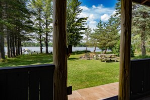 A wooden deck overlooking a grassy area with picnic tables and a lake. - Water lovers Dream! Gorgeous modern updates with a rustic flare! (Lake Linden)