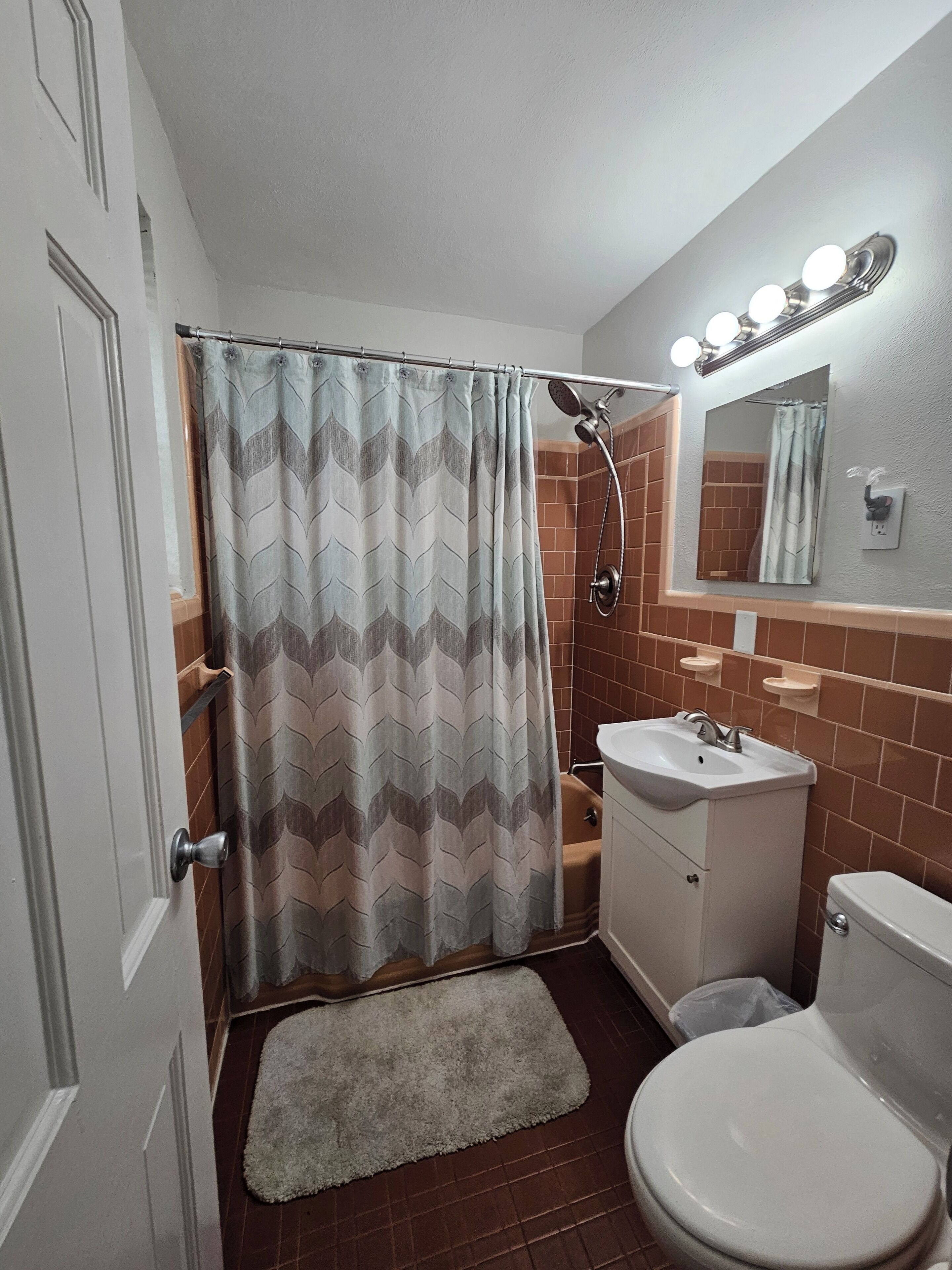 Une salle de bain équipée d’une douche, d’un lavabo, de toilettes et d’un miroir avec éclairage.