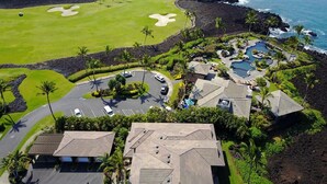 A golf course with bunkers, a pool area, and a view of the ocean.