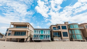 Ein strandnahes Anwesen mit modernem Design, bestehend aus einem zweistöckigen Gebäude mit großen Fenstern und einem Balkon.