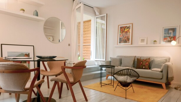 Ein modernes Wohnzimmer mit einer Couch, Sesseln, einem Couchtisch und einem Essbereich mit Stühlen und einem Tisch.