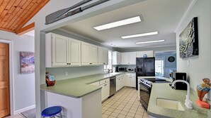 Une cuisine moderne avec des meubles blancs, un îlot central, un four à micro-ondes, un réfrigérateur et une machine à café.