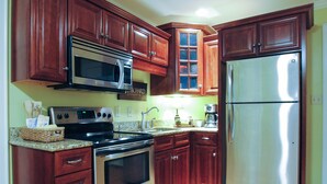 A kitchen with wooden cabinets, stainless steel appliances, and a granite countertop. - A historical hideaway (Cleveland)