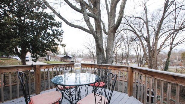 A round glass table with metal chairs on a wooden deck, overlooking a residential area. - A historical hideaway (Cleveland)