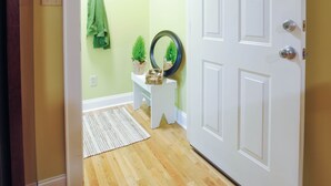 A hallway with a white door, a small white bench, a green towel hanging, a small plant, and a decorative mirror on the wall. - A historical hideaway (Cleveland)
