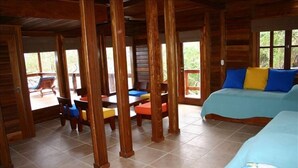 Eine Holzhütte mit Essbereich und zwei Betten mit farbenfroher Bettwäsche.