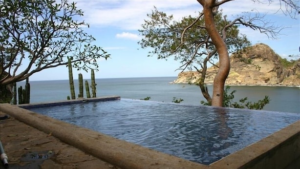 Ein Pool mit freiem Blick auf das Meer und einer felsigen Klippe im Hintergrund.
