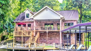 A two-story house with a dock and a covered area with chairs. - Centrally Located Lake House with a Secluded Feel Boat Slip Included (HOT SPRINGS NATIONAL PARK)