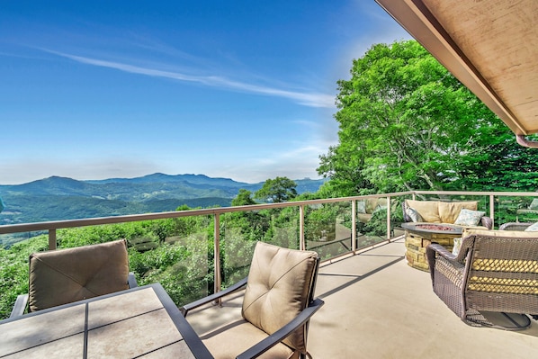 A balcony with a clear view of mountains and lush greenery.