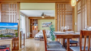 Camera d'albergo con zona pranzo, un letto, una TV e vista su un edificio.