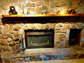 Cozy fireplace with a mantel shelf, featuring decorative items and a metal screen.