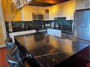 Enjoy cooking in this well-equipped kitchen with a large island, stainless steel appliances, and ample counter space.