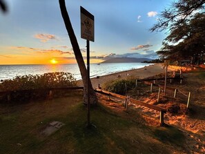 A sunset view over a beach with a sign warning of strong currents. - Artistic Top-Floor Tropical Penthouse – Steps to Maui’s Best Beach (Kihei)
