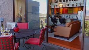 A modern kitchen with colorful cabinets, a dining area with red chairs, and a balcony with a table and chairs. - Artistic Top-Floor Tropical Penthouse – Steps to Maui’s Best Beach (Kihei)