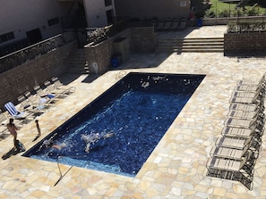 Relax by the pool surrounded by lounge chairs and a staircase leading to an upper level.