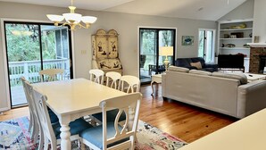 A spacious living area with a dining table, chairs, a sofa, and a fireplace. - Precious Island Cottage (Fripp Island)