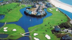 A golf course with a central island, water bodies, and a beach in the background. - Precious Island Cottage (Fripp Island)