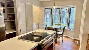 A kitchen with a central island, wooden cabinets, a built-in oven, and a dining table with chairs. - Precious Island Cottage (Fripp Island)