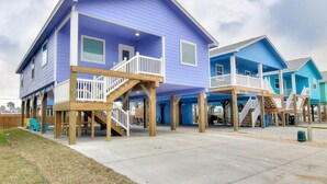 Una propiedad frente al mar con dos casas azules, terrazas de madera y barandillas.