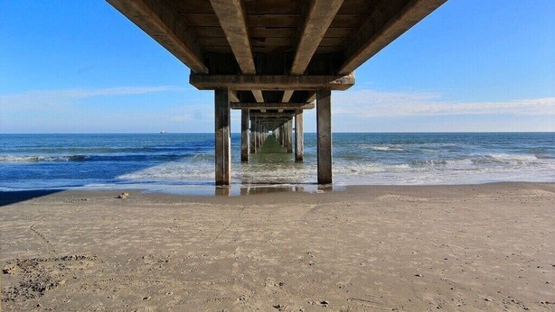 Un muelle que se adentra en el océano con una vista despejada del agua y del cielo.