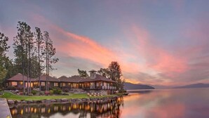 A lakeside resort with multiple cabins, a dock, and a calm lake reflecting the sunset.