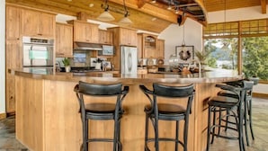 A spacious kitchen with wooden cabinets, a central island with bar stools, and a large window providing natural light.