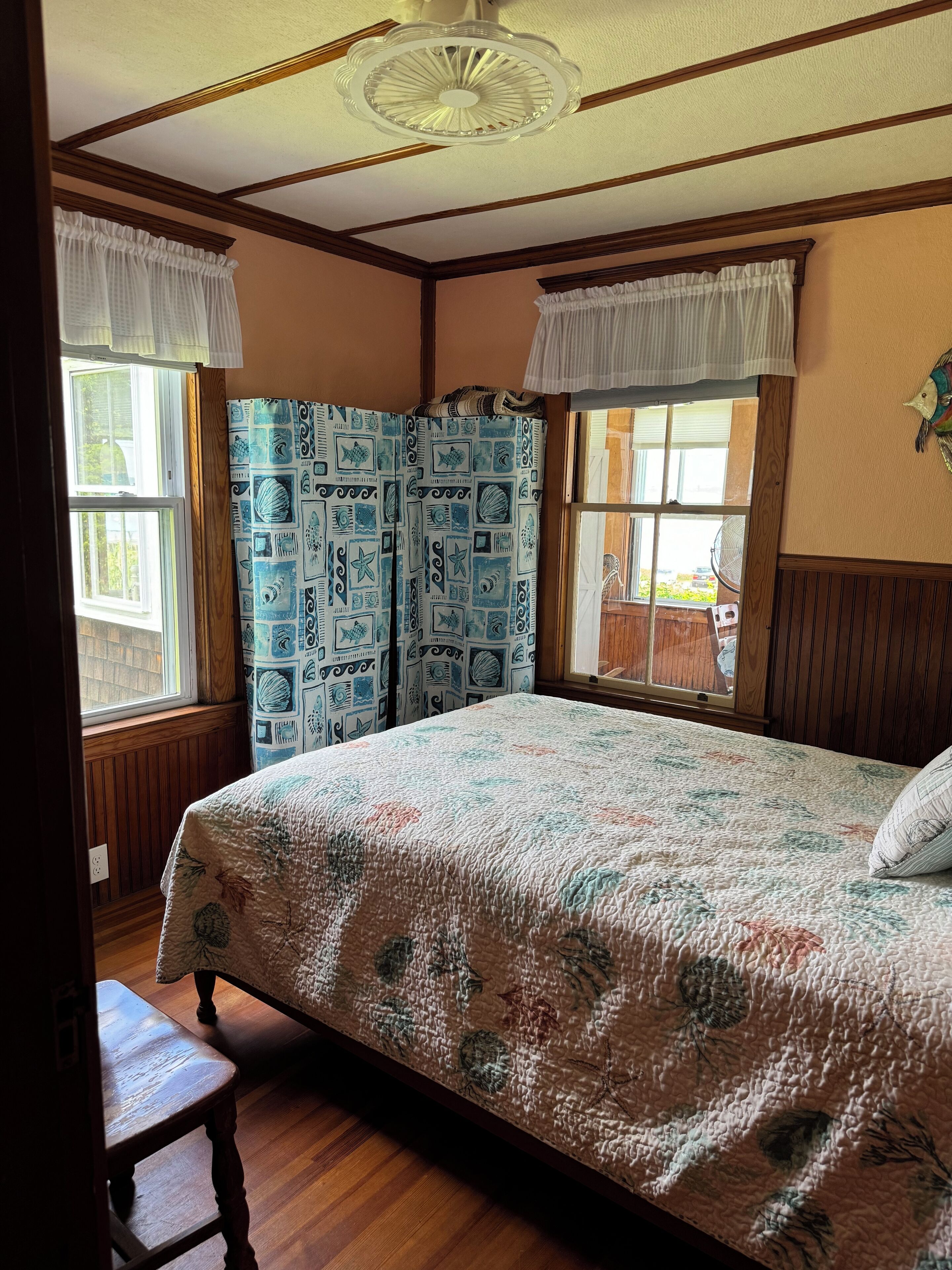 Un dormitorio con una cama grande, piso de madera y una ventana con cortinas.