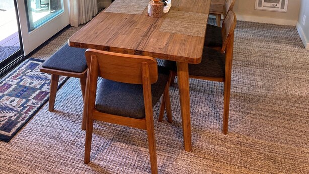 Un coin repas avec une table et des chaises en bois, un ventilateur de plafond et une vue à travers une porte vitrée.