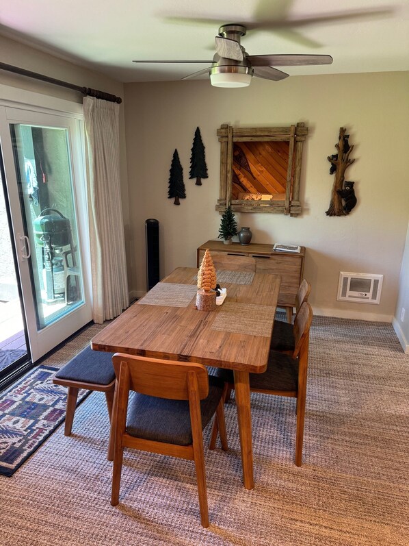 A dining area with a wooden table and chairs, a ceiling fan, and a view through a glass door. - Snowcreek, in the meadow! (Mammoth Lakes)