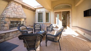 Un patio al aire libre con muros de piedra, muebles de mimbre y una chimenea.