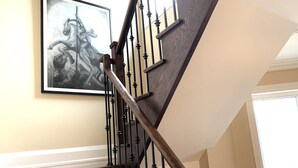 Eine Holztreppe mit schwarzen Geländern und einem gerahmten Kunstwerk darüber.