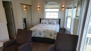 Ein Schlafzimmer mit einem Bett, zwei Sesseln, einem kleinen Tisch und einem Fenster mit Jalousien.