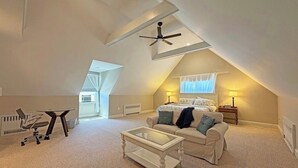 Ein Schlafzimmer im Loft-Stil mit schrägverdeckter Decke, einem Bett, einem Schreibtisch und einem Stuhl.