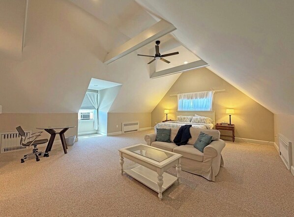 A loft-style bedroom with a sloped ceiling, a bed, a desk, and a chair.