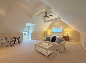 Une chambre de style « loft », avec un plafond en pente, un lit, un bureau et une chaise.