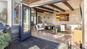 An open-plan living area with a dining table, sofa, and a glass door leading to a patio. - Luxury beach vacation - Ocean view bright and fun (Manhattan Beach)