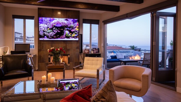 A modern living room with a large TV, comfortable seating, a fireplace, and a view of the city. - Luxury beach vacation - Ocean view bright and fun (Manhattan Beach)