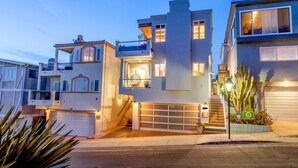 A modern multi-story residential building with a garage, a balcony, and a staircase leading to the upper levels. - Luxury beach vacation - Ocean view bright and fun (Manhattan Beach)